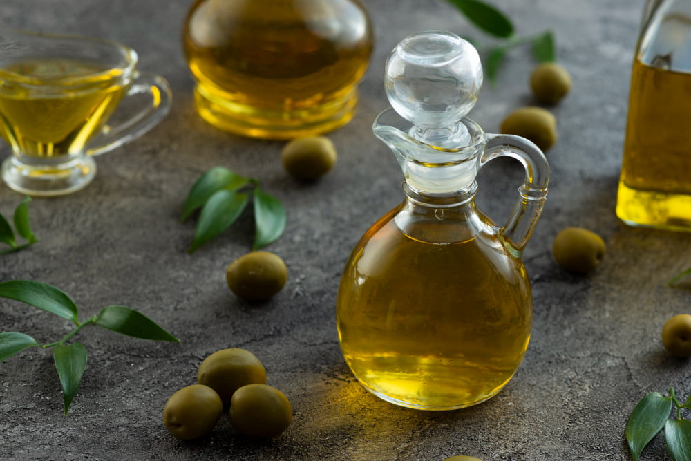 Quais os Alimentos que melhoram a circulação sanguínea? 3 high view bottles filled with olive oil marble background